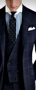 Man wearing a bespoke dark blue windowpane check 3-piece suit paired with a striped shirt and polka dot tie, highlighting expert formal tailoring at From Collars to Cuffs in Weston, Florida