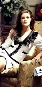Woman sitting in a custom white tweed jacket featuring black ruffle details and trim, representing elegant bespoke women's fashion and luxury craftsmanship at From Collars to Cuffs in Weston, FL.