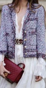 Woman wearing a custom light purple tweed jacket over a white dress holding a red handbag, showcasing bespoke Chanel-inspired luxury fashion at From Collars to Cuffs in South Florida
