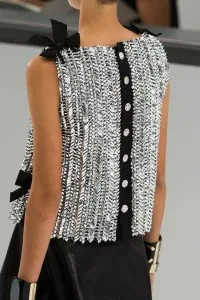 Model wearing a custom one-shoulder silver sequined top with black button details and bow accents, representing luxury bespoke women's evening wear at From Collars to Cuffs in Weston, Florida