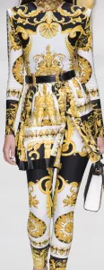 Model wearing a custom gold and black baroque patterned dress or tunic with matching pants and a black belt, highlighting bold luxury bespoke women's fashion at From Collars to Cuffs in South Florida