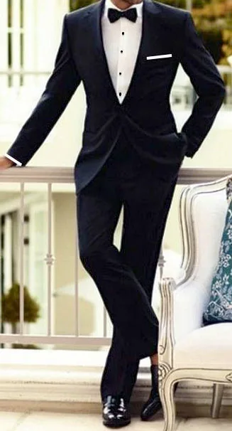 Model wearing a custom navy velvet tuxedo with black bow tie and patent leather shoes, showcasing sophisticated bespoke formal fashion at From Collars to Cuffs in South Florida.