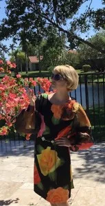 Woman wearing a custom black dress with vibrant orange floral print and sunglasses, showcasing bold bespoke women's fashion at From Collars to Cuffs in Weston, South Florida