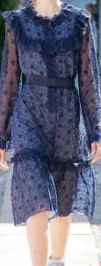 Woman wearing a custom navy blue sheer lace dress with a black belt, showcasing elegant bespoke women's fashion and intricate fabric detailing at From Collars to Cuffs in South Florida