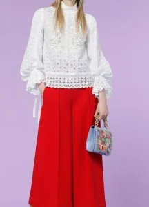 Woman wearing a custom white lace blouse with red wide-leg trousers and a floral bag, showcasing sophisticated bespoke women's fashion at From Collars to Cuffs in Weston, Florida