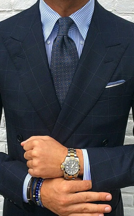 Close-up of a man wearing a custom dark blue double-breasted suit and checking his watch, showcasing luxury bespoke menswear and precise tailoring at From Collars to Cuffs in South Florida