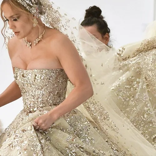 Bride in a custom strapless gold sequin and beaded wedding gown with a matching veil and necklace, representing luxury bespoke bridal fashion at From Collars to Cuffs in Weston, Florida