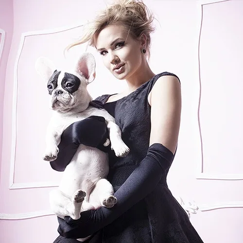 Elegant woman in custom black haute couture dress holding French bulldog, showcasing bespoke luxury fashion and personalized tailoring at From Collars to Cuffs boutique in Weston, South Florida