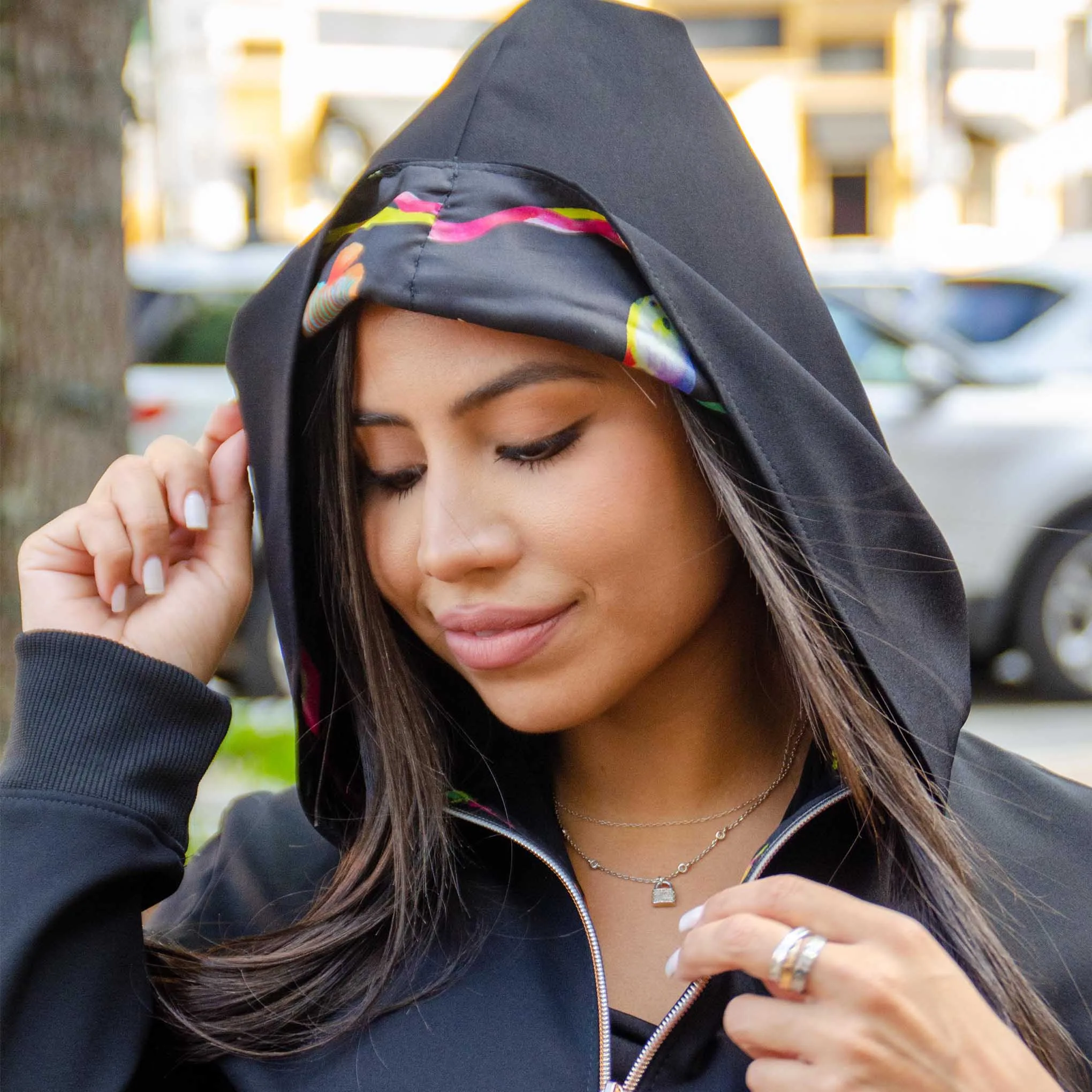 Close-up profile of a woman in a custom black hooded jacket with gold accents and vibrant scarf detail, representing high-end bespoke casual fashion at From Collars to Cuffs in South Florida