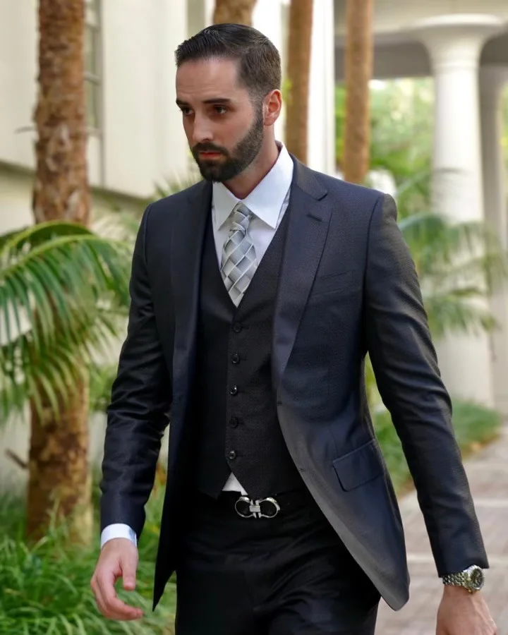 Man in a custom dark grey 3-piece suit walking outdoors, highlighting expert tailoring details and luxury fabric selection for Miami and South Florida clients at From Collars to Cuffs