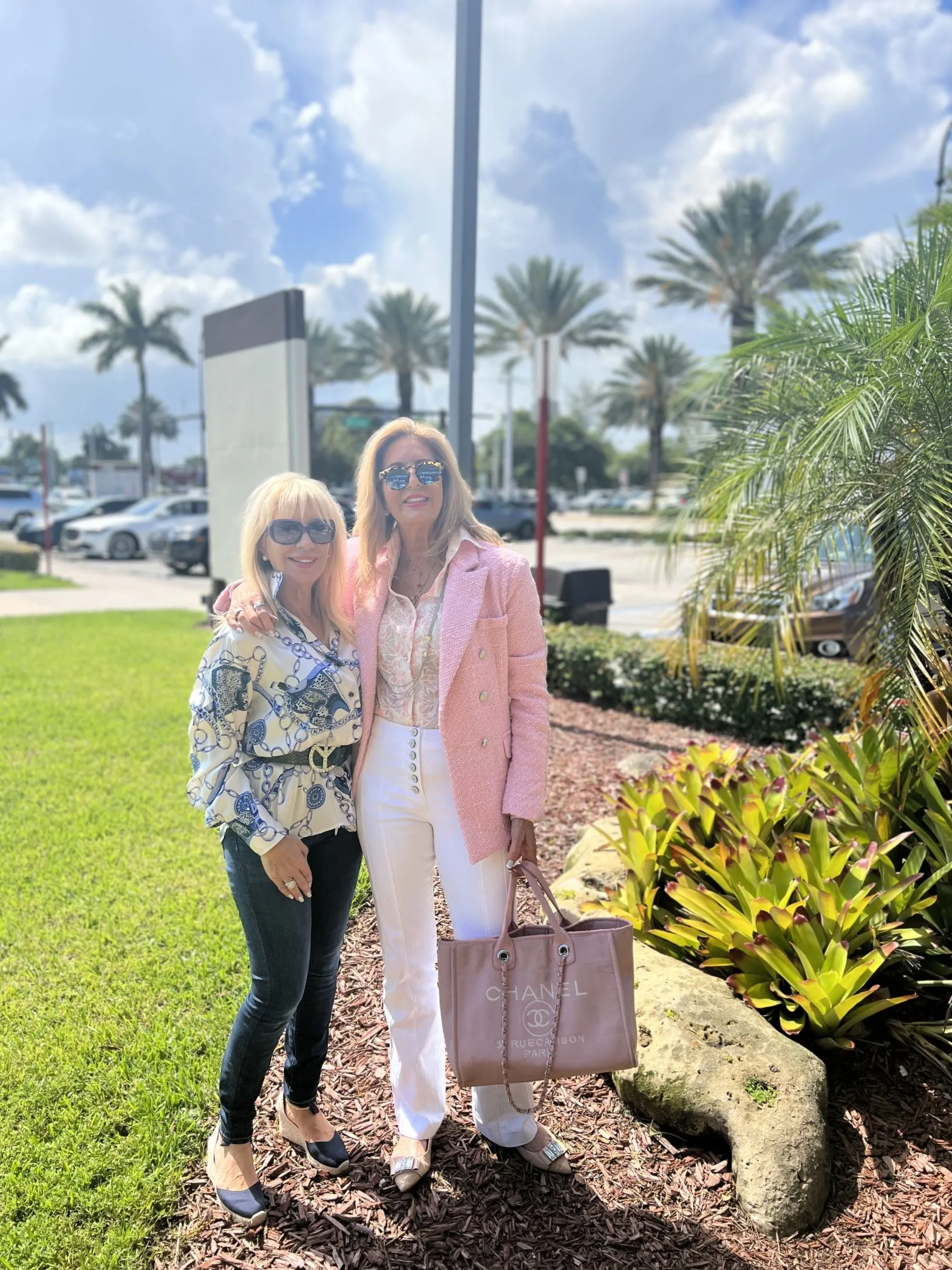 Two women in custom pink and blue silk Chanel-inspired outfits with matching bags, representing luxury spring fashion and bespoke tailoring at From Collars to Cuffs in Weston Town Center, Florida